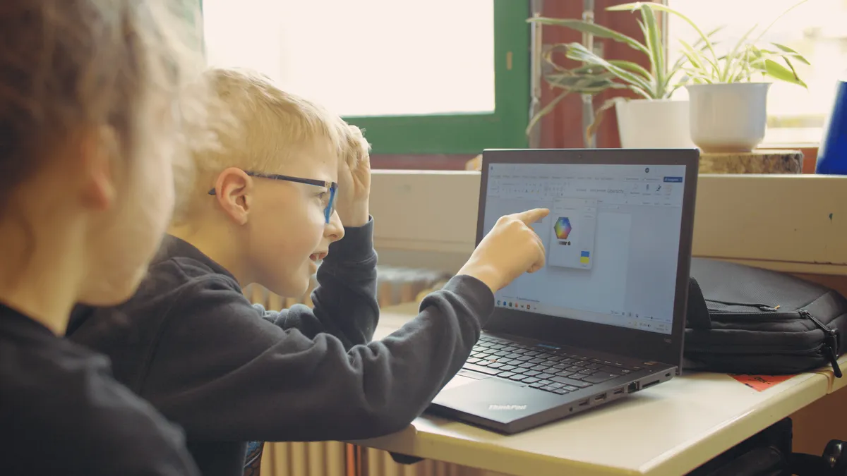 Kind malt auf einem Laptop